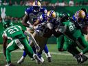 Les Roughriders de la Saskatchewan tentent d'arrêter le porteur de ballon des Blue Bombers de Winnipeg Brady Oliveira lors d'un match du 16 juin à Regina. 