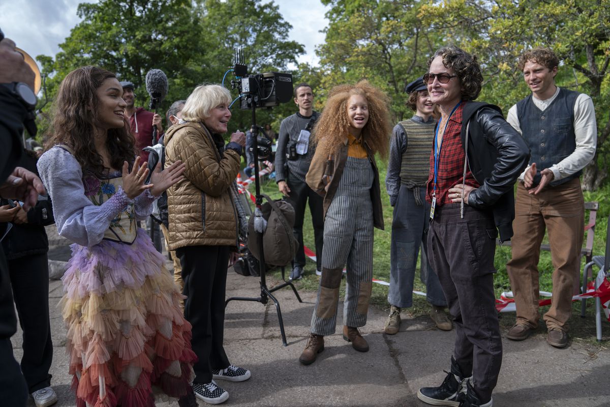 Nina Jacobson, Rachel Zegler et un groupe de figurants du District 12 se tiennent debout sur The Hunger Games : La Ballade des oiseaux chanteurs et des serpents