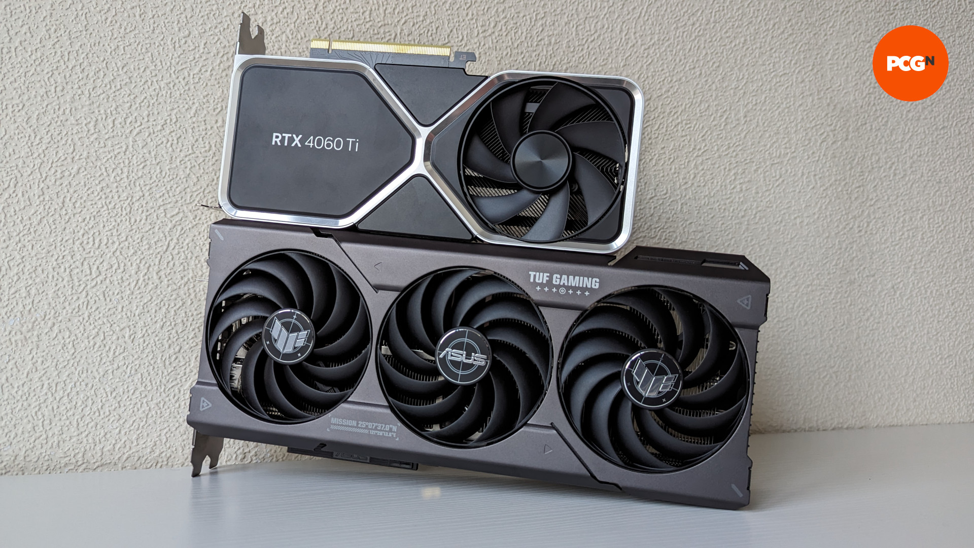 Test de l'AMD Radeon RX 7700 XT : Le modèle ASUS TUF Gaming de la carte graphique repose sur une surface en bois blanc, avec une Nvidia GeForce RTX 4060 Ti Founders Edition posée dessus