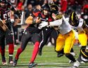 Le quart-arrière des Redblacks d'Ottawa Dustin Crum dirige le ballon contre Jonathan Kongbo des Tiger-Cats de Hamilton vendredi soir.  Matt Zambonin/LA PRESSE CANADIENNE