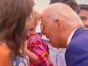 Le président américain Joe Biden se penche sur une petite fille tenue par sa mère.