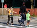 Un brigadier scolaire aide un parent à accompagner un enfant à l'école à Ottawa pour la première fois cette année.  Les températures à Ottawa et dans l'ouest du Québec continuent de monter en flèche.