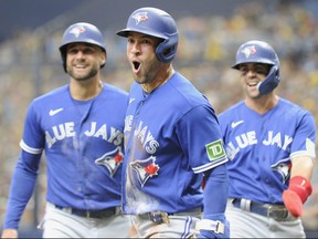 George Springer (au centre), outfielder des Blue Jays de Toronto, célèbre sa deuxième course à domicile de trois repas à l'intérieur du parc contre les Rays de Tampa Bay.