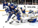 L'avant des Maple Leafs de Toronto Fraser Minten renverse le denfenceman des Sabres de Buffalo Norman Ponacha devant le gardien de but Ukko-Pekka Luukkonen lors du match pré-saison de la LNH de Kraft Hockeyville au centre communautaire Joe Thornton à St. Thomas, en Ontario.