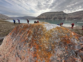 Un lichen ancien et des randonneurs d'Adventure Canada beaucoup plus jeunes à Cuming Inlet.