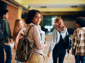 adolescente dans le couloir du lycée regardant la caméra