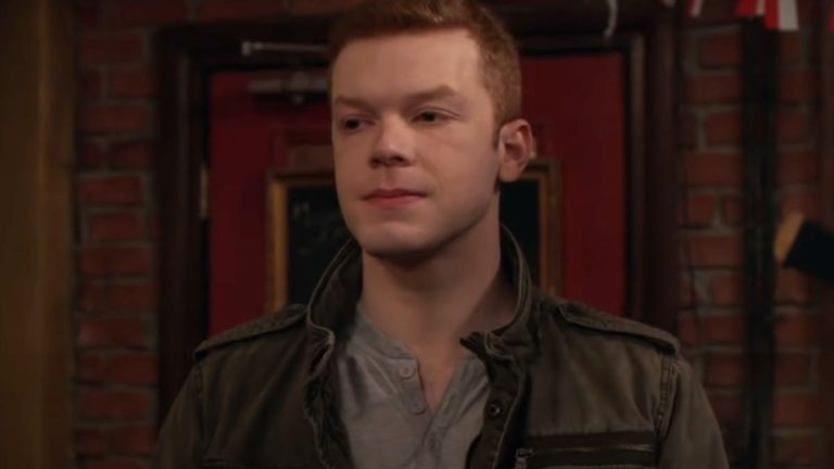 Cameron Monaghan stands in a bar, looking uncertain, in Shameless.