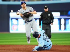 L'arrêt-court des Texas Rangers Corey Seager (à gauche) force Matt Chapman (26 ans) des Blue Jays de Toronto à la deuxième base alors qu'il se lance au premier lors de la deuxième manche de l'action de la MLB à Toronto le jeudi 14 septembre 2023.