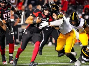 Le quart-arrière des Redblacks d'Ottawa Dustin Crum dirige le ballon contre Jonathan Kongbo des Tiger-Cats de Hamilton vendredi soir.  Matt Zambonin/LA PRESSE CANADIENNE