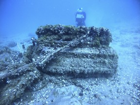 Cette photo du 17 août 2021 montre des moules quagga recouvrant le moteur d'un avion militaire Bell P-39 Airacobra dans le lac Huron, Michigan, alors que l'archéologue maritime Carrie Sowden, à l'arrière, documente le site.