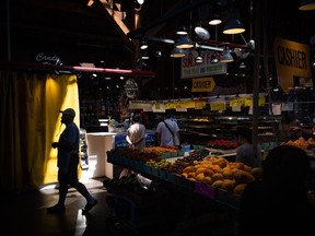 Une personne se profile alors que des gens achètent des produits au marché de Granville Island à Vancouver, le mercredi 20 juillet 2022.