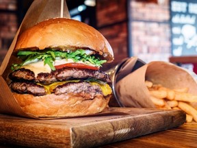 Un hamburger et des frites sont visibles sur une table en bois dans un restaurant.