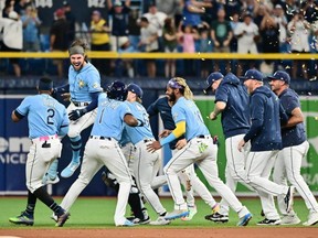 Le frappeur des Rays Josh Lowe (deuxième à gauche) célèbre avec ses coéquipiers après avoir frappé un simple RBI en neuvième manche pour vaincre les Blue Jays 7-6 au Tropicana Field de Saint-Pétersbourg, en Floride, le samedi 23 septembre 2023.