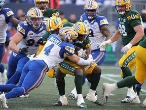 Le défenseur des Blue Bombers de Winnipeg Adam Bighill affronte le porteur de ballon des Elks d'Edmonton Kevin Brown lors du premier quart de la LCF à Winnipeg plus tôt cette saison.