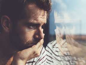 Un jeune homme triste regarde par la fenêtre