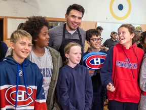 Le capitaine des Canadiens Nick Suzuki pose pour des photos avec des élèves de l'école primaire Maple Grove à Lachine, lundi.