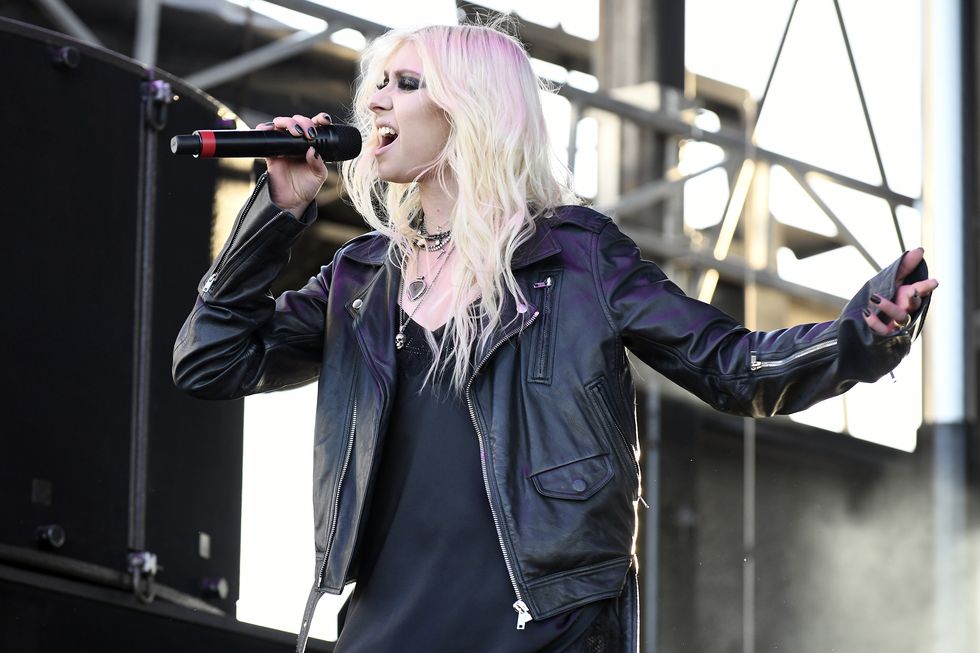 taylor momsen, une jeune femme chante sur scène, elle a les cheveux blonds et le maquillage des yeux foncés, elle porte une robe noire avec une veste en cuir