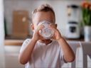 Le petit garçon a presque fini de boire un verre de lait.