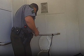 Sur cette photo publiée par la police de l'État du Michigan, un sergent du ministère des Ressources naturelles s'entretient avec une femme qui s'est retrouvée coincée dans les toilettes d'une dépendance après avoir tenté de récupérer son Apple Watch, le mardi 19 septembre 2023, à Dixon Lake, dans le canton de Bagley. Michigan