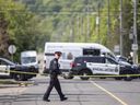 Un policier traverse la rue sur les lieux d'une enquête pour homicide dans le secteur de Jones Road et Barton Street à Hamilton, en Ontario.  Dimanche 28 mai 2023.