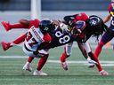 Le receveur large des Alouettes de Montréal Kevin Kaya est plaqué par les arrières défensifs des Rouge et Noir d'Ottawa Brandin Dandridge (37 ans) et Abdul Kanneh plus tôt cette saison.