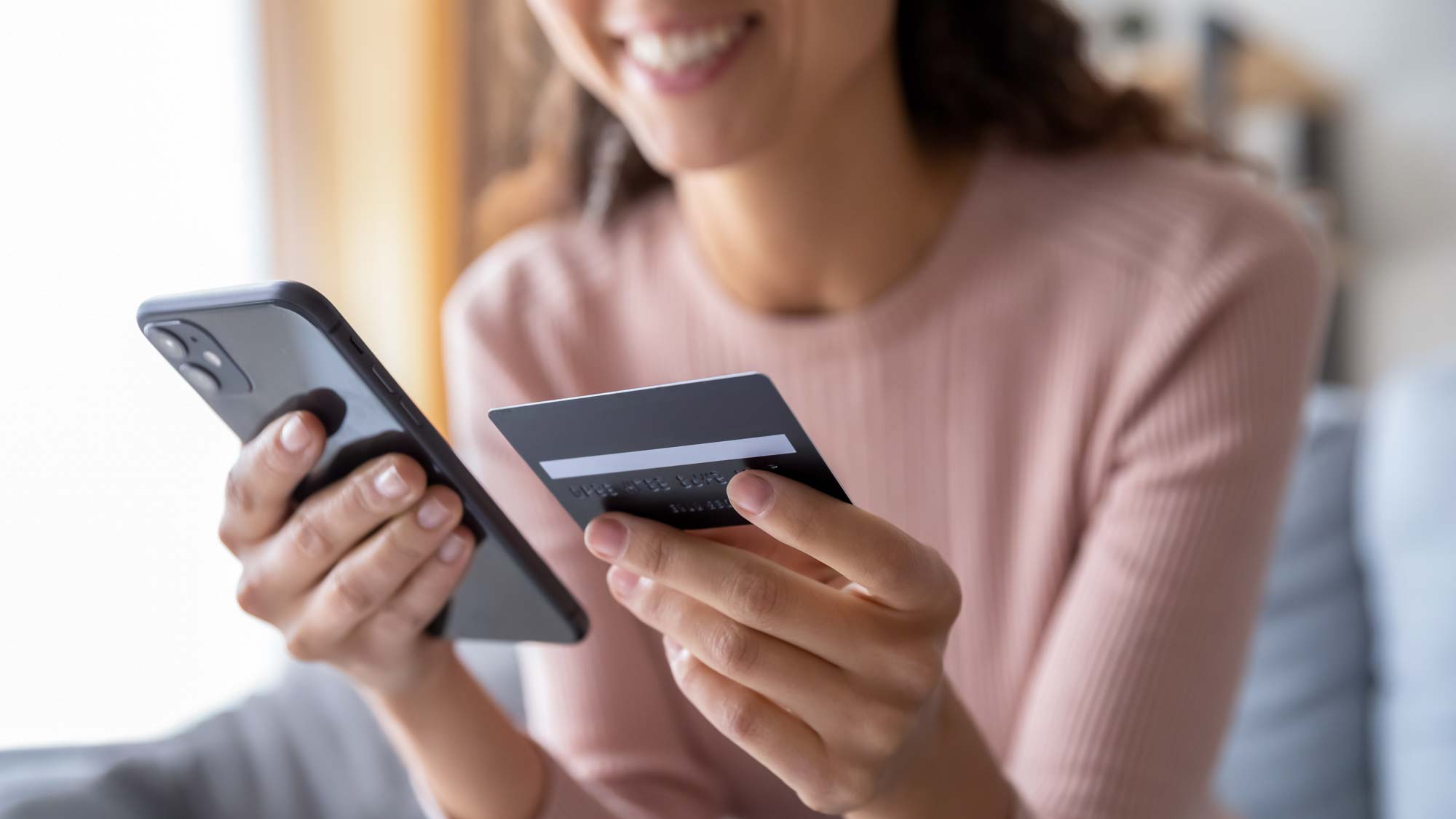 Femme tenant un téléphone et une carte de crédit dans ses mains