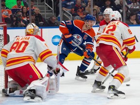 Connor McDavid affronte un trio de défenseurs des Flames devant le filet de Calgary