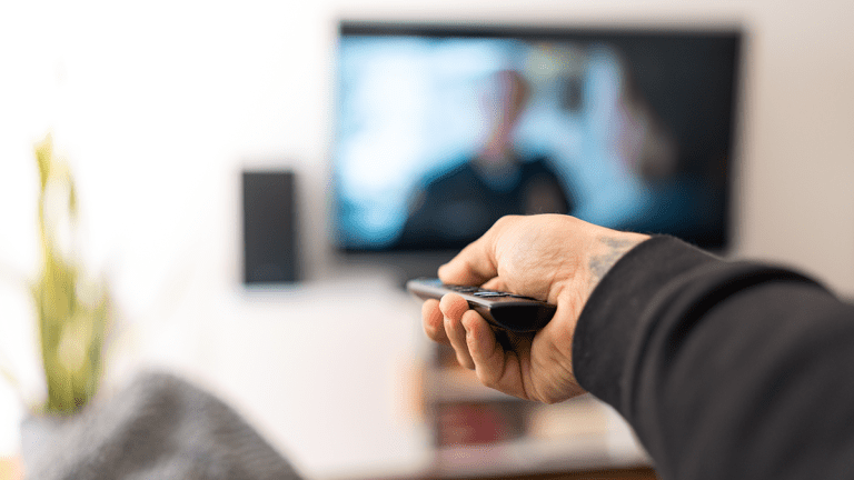 A man on sofa changing the TV channel