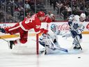 L'ailier droit des Red Wings Christian Fischer (à gauche) est déclenché sous le regard du gardien de but des Maple Leafs Joseph Woll et du centre des Maple Leafs Fraser Minten (à droite) pendant la deuxième période de l'action préparatoire de la LNH à Détroit, le samedi 7 octobre 2023.