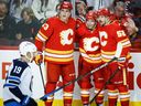 L'attaquant des Flames de Calgary Matthew Coronato, au centre droit, célèbre son but avec Adam Ruzicka, au centre gauche, et MacKenzie Weegar alors que David Gustafsson des Jets de Winnipeg passe devant le Scotiabank Saddledome à Calgary, le lundi 2 octobre 2023.