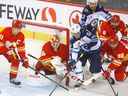 Le gardien de but des Flames de Calgary, Jacob Markstrom, cherche à dégager la rondelle de l'attaquant des Jets de Winnipeg Mark Scheifele au Scotiabank Saddledome de Calgary, le mercredi 11 octobre 2023. 