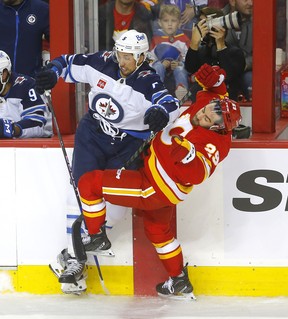 Le défenseur des Jets Brenden Dillon présente l'attaquant des Flames Dillon Dubé lors du match d'ouverture de la saison mercredi à Calgary.