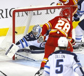 Elias Lindholm des Flames marque le but gagnant en fin de troisième période contre le gardien des Jets Connor Hellebuyck.