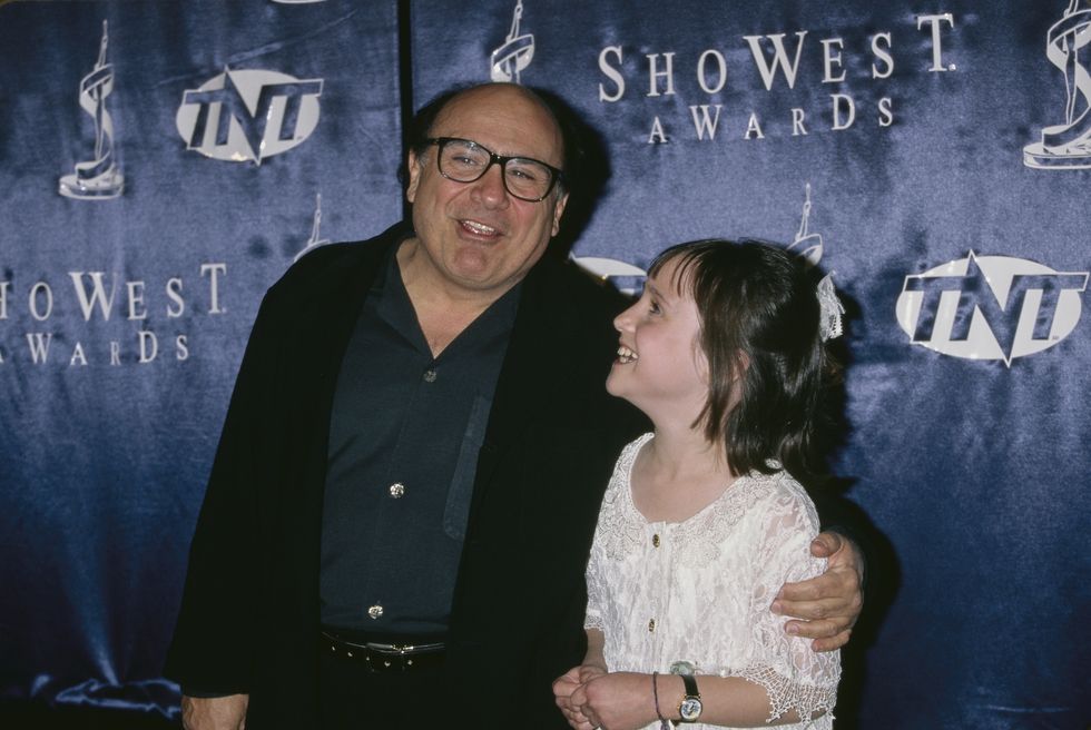 Danny Devito et Mara Wilson sourient et s'embrassent lors d'un événement sur le tapis rouge en 1997.