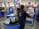 Un caissier place des articles dans le panier d'un client dans un magasin Walmart en Californie.