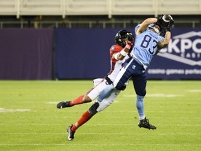 Le receveur des Argonauts de Toronto David Ungerer III reçoit une passe du quart-arrière Chad Kelly, tandis que le demi défensif des Redblacks d'Ottawa Alijah McGhee tente d'intercepter à Toronto hier soir.  Pour en savoir plus, visitez ottawasun.com.  Christopher Katsarov/LA PRESSE CANADIENNE