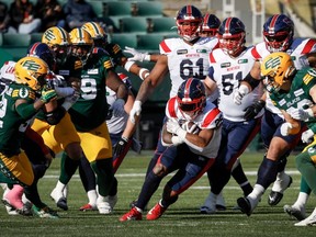 Le porteur de ballon des Alouettes Walter Fletcher, au centre, passe le ballon devant les joueurs des Elks d'Edmonton, à Edmonton, le samedi 14 octobre 2023.