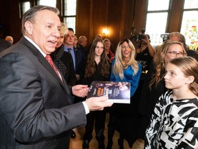 Le premier ministre François Legault s'entretient avec les membres de la famille du joueur de hockey Mike Bossy lors du lancement d'un livre à Montréal, le lundi 16 octobre 2023. Legault affirme que son gouvernement de la Coalition Avenir Québec savait que la décision d'augmenter les frais de scolarité dans les universités anglaises serait controversée, mais "quand je regarde le nombre d’étudiants anglophones au Québec, cela menace la survie du français.