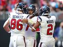 Dalton Schultz, CJ Stroud et Robert Woods des Texans de Houston célèbrent après avoir marqué un touché.