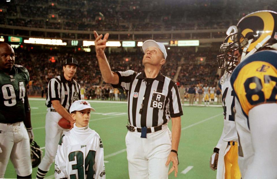 PHI02:SPORT-NFL:PHILADELPHIA,PENNSYLVANIA,3DEC98 - l'arbitre de la NFL Bernie Kukar (C) lance la pièce au début du match de la NFL du 3 décembre entre les Eagles de Philadelphie et les Rams de St. Louis.  La NFL a institué de nouvelles règles pour le tirage au sort à la suite d'un appel controversé lors du match du 26 novembre entre les Lions de Détroit et les Steelers de Pittsburgh.  Le juge arrière Bill Leavy regarde par derrière, tout comme le fan des Eagles Mike Jenelli (34 ans).  BKS