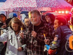 Brian Sweeney, au centre, père d'Angie Sweeney, victime de la fusillade, est vu lors d'une veillée aux chandelles avec son fils et la mère du tireur, Marcia Gillespie, à Sault Ste.  Marie, Ontario, le vendredi 27 octobre 2023.