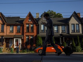 Une personne passe devant une rangée de maisons à Toronto.