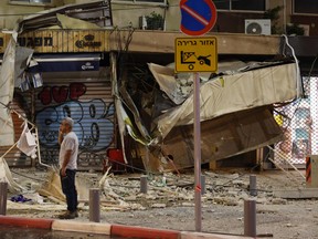 Un homme se tient devant un magasin endommagé à Tel Aviv, après qu'il ait été touché par une roquette tirée par des militants palestiniens depuis la bande de Gaza, le 7 octobre 2023.