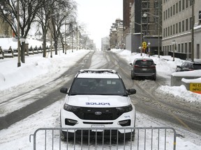 Un agent de la Police d'Ottawa est assis dans sa voiture de patrouille sur la rue Wellington, en contrebas de la Colline du Parlement, à Ottawa, le vendredi 27 janvier 2023.