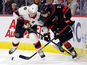 Brady Tkachuk des Sénateurs d'Ottawa se bat pour la rondelle contre Brett Pesce des Hurricanes de la Caroline au cours de la première période à Raleigh, en Caroline du Nord, le mercredi 11 octobre 2023.