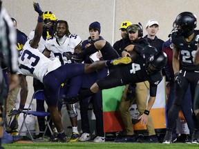 Le quart-arrière de l'État du Michigan, Sam Leavitt (4), est frappé hors des limites par le demi défensif du Michigan DJ Waller Jr. (13), le samedi 21 octobre 2023, à East Lansing, Michigan.