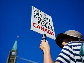 Un manifestant tient une pancarte indiquant « Abandonnons les combustibles fossiles Canada »