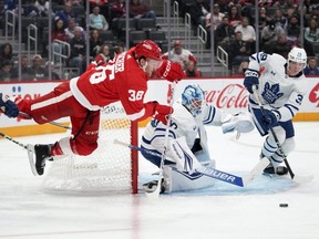 L'ailier droit des Red Wings Christian Fischer (à gauche) est déclenché sous le regard du gardien de but des Maple Leafs Joseph Woll et du centre des Maple Leafs Fraser Minten (à droite) pendant la deuxième période de la pré-saison de la LNH à Détroit, le samedi 7 octobre 2023.