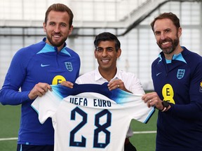 Le Premier ministre britannique Rishi Sunak (C) pose avec l'attaquant anglais Harry Kane (L) et le directeur Gareth Southgate lors d'une visite au parc St George's.