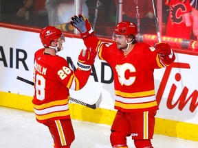 Rasmus Andersson des Flames de Calgary marque sur le gardien des Jets de Winnipeg Connor Hellebuyck en deuxième période du match d'ouverture à domicile au Scotiabank Saddledome de Calgary, le mercredi 11 octobre.